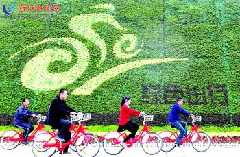 市民騎公共自行車路過市人民廣場(chǎng)一處花壇。記者 張馳